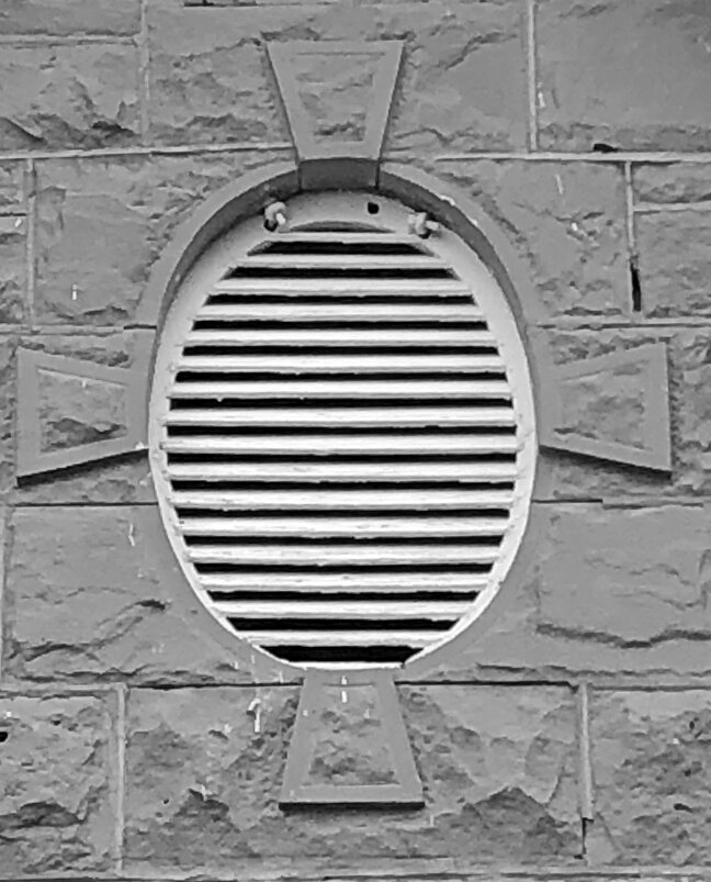 An oval vent in dressed sandstone